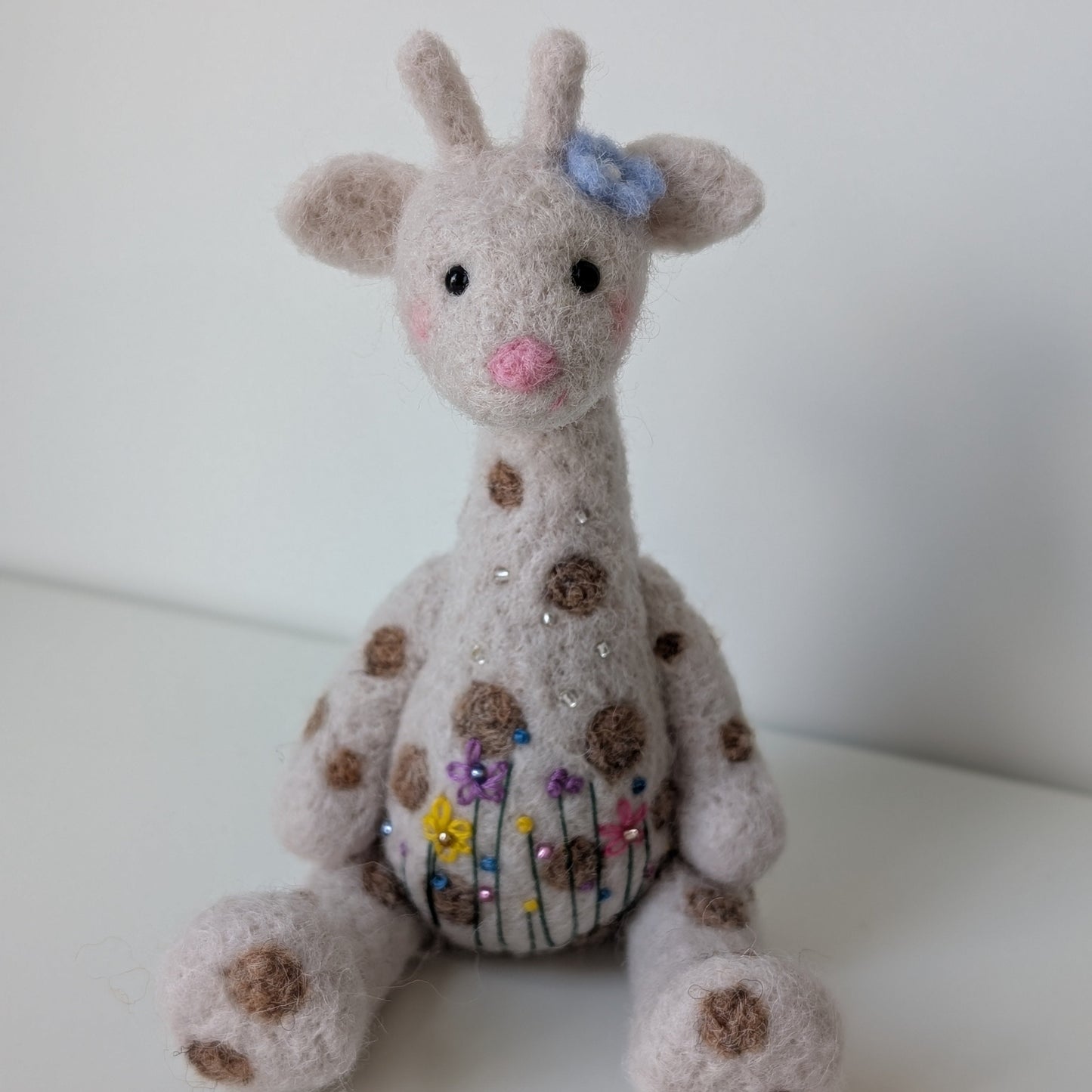 needlefelted giraffe with a bow and floral embroidery