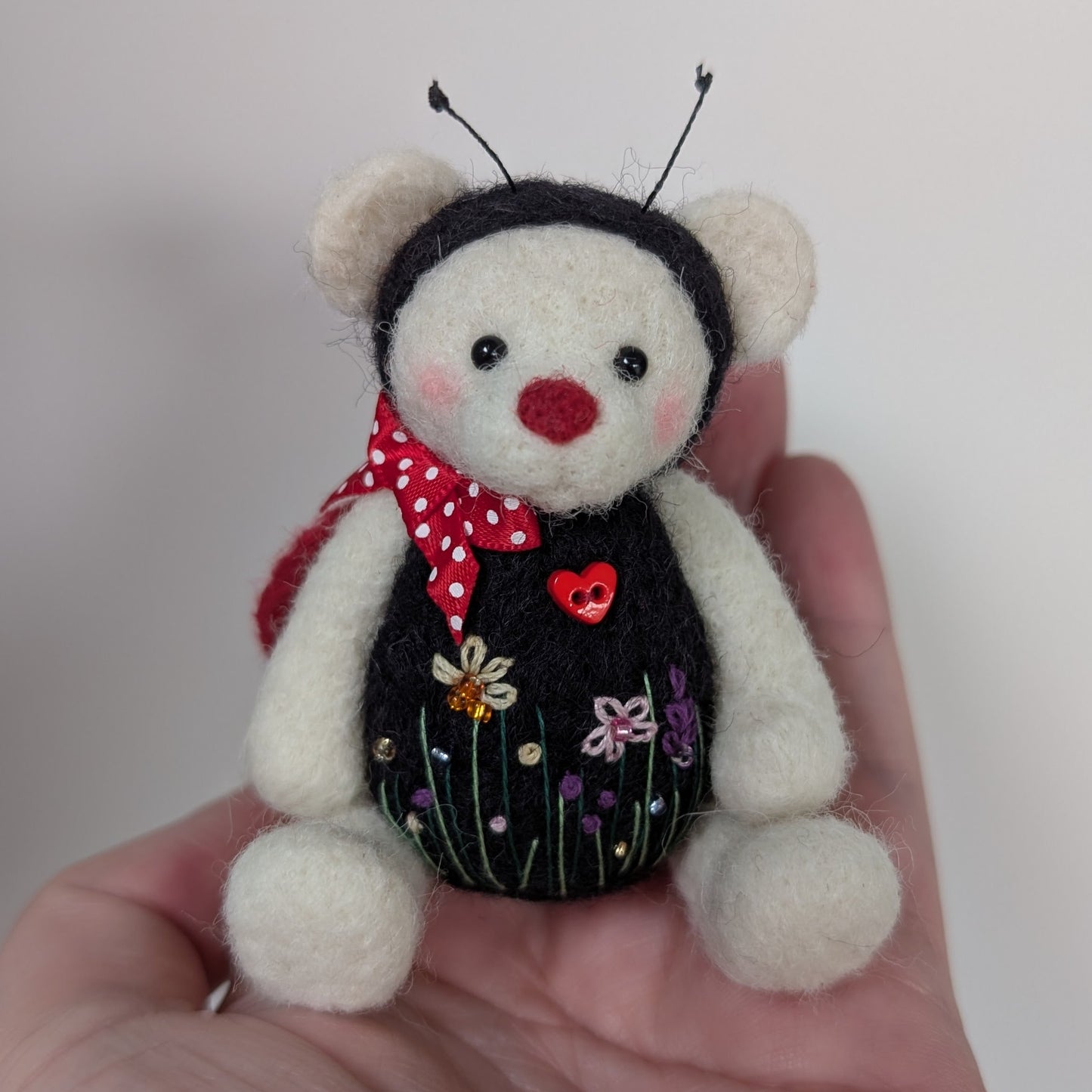 needlefelt teddy bear dressed as a ladybird, with floral embroidery