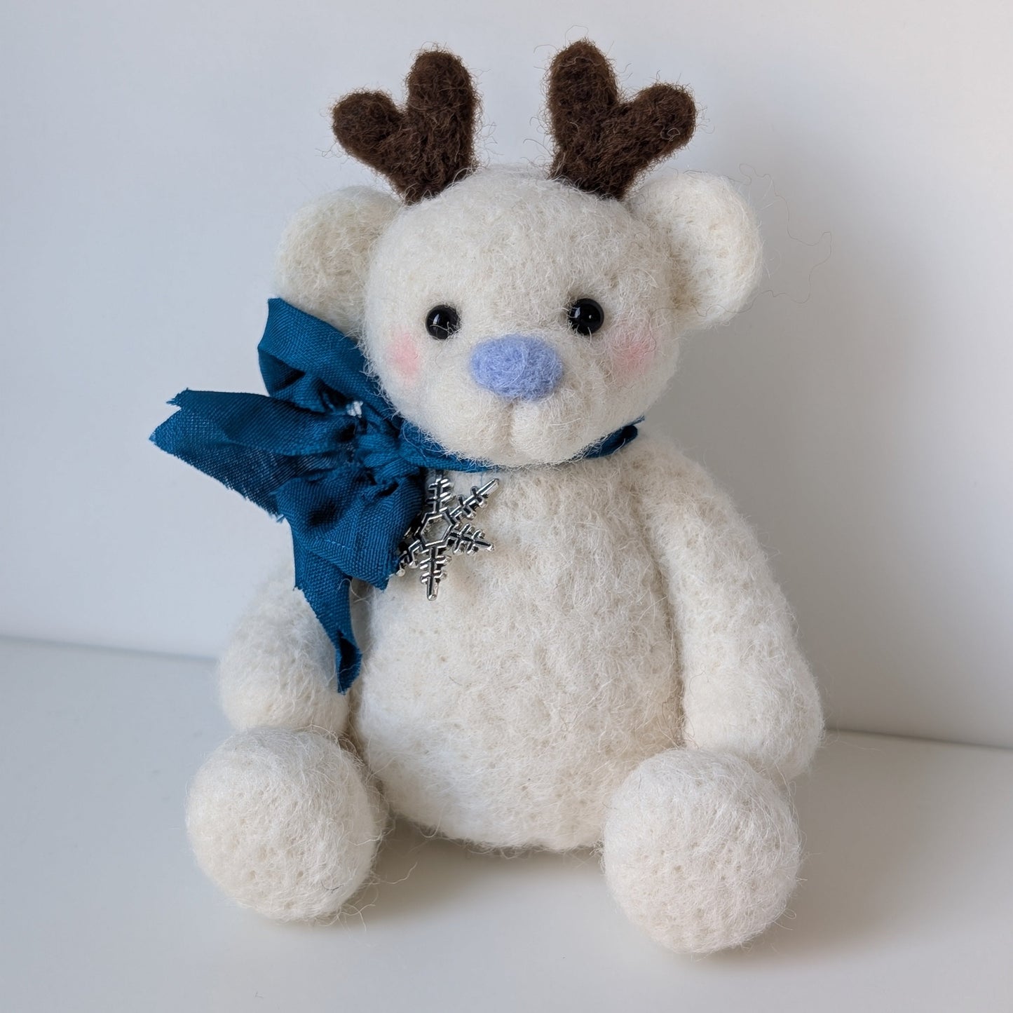 white bear with blue ribbon and nose with reindeer antlers