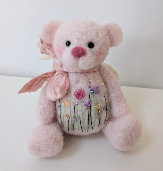 pale pink needlefelted teddybear with pastel flowers embroidered on the tummy